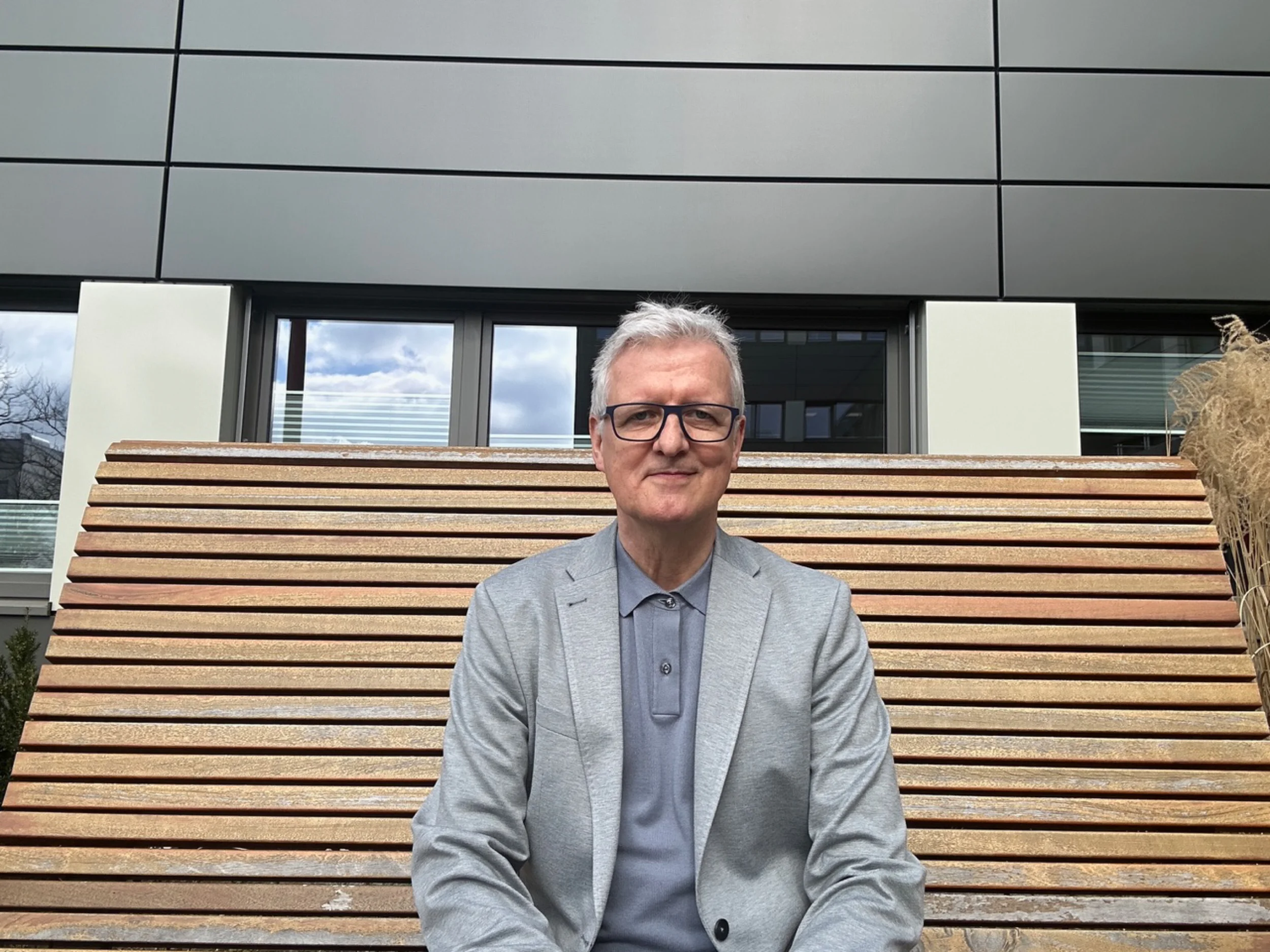 Körpersprache und Gestik Martin sitzt auf einer Holzbank.